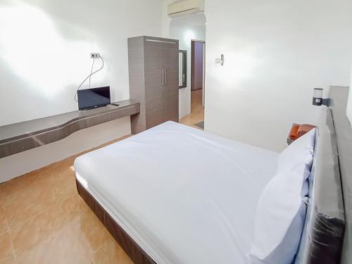 um quarto branco com uma cama e uma televisão em RedDoorz Syariah near Q-Mall Banjarbaru em Martapura