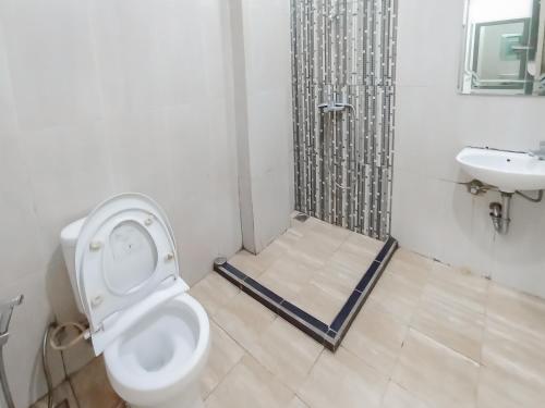 a bathroom with a toilet and a sink at RedDoorz Syariah near Q-Mall Banjarbaru in Martapura