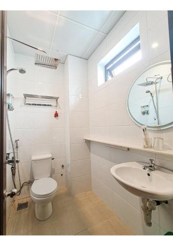 a white bathroom with a toilet and a sink at Quan Quan Hotel in Da Nang