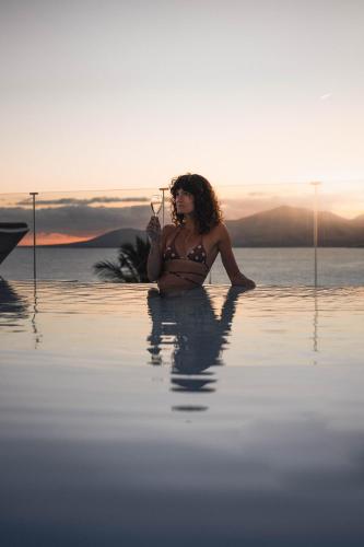 a woman sitting in the water in a body of water at Hotel Fariones in Puerto del Carmen