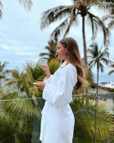 a woman in a white dress holding a cup of coffee at Hotel Fariones in Puerto del Carmen