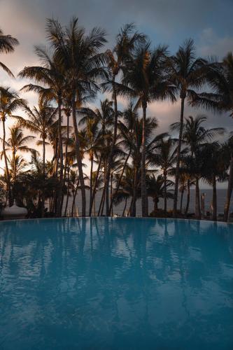 a large swimming pool with palm trees in the background at Hotel Fariones in Puerto del Carmen