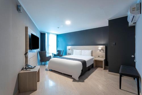 a bedroom with a white bed and a blue wall at Gyeongpo Soo Hotel in Gangneung