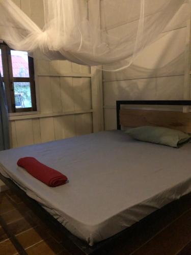 Bett in einem Zimmer mit einem roten Kissen darauf in der Unterkunft Macondo in Koh Rong Sanloem