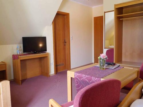 a living room with a table and a tv at Da`Sporrer Hotel & Wirtshaus in Neunburg vorm Wald