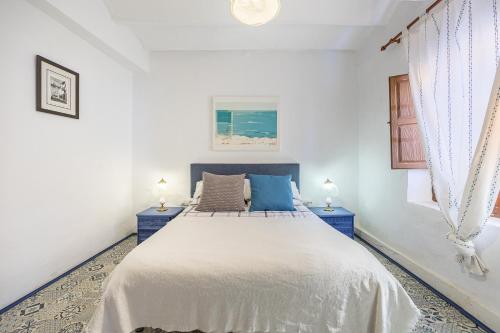 ein weißes Schlafzimmer mit einem großen Bett mit blauen Akzenten in der Unterkunft Casa Rural La Clau in Polop