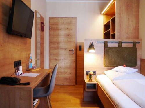Schlafzimmer mit einem Schreibtisch und einem Bett mit einem Computer in der Unterkunft Da`Sporrer Hotel & Wirtshaus in Neunburg vorm Wald