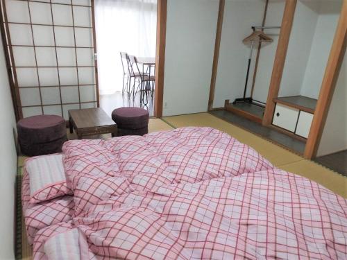 阿蘇市にあるGuest House Asoraのベッドルーム1室(ピンクのチェックされた毛布付きのベッド1台付)