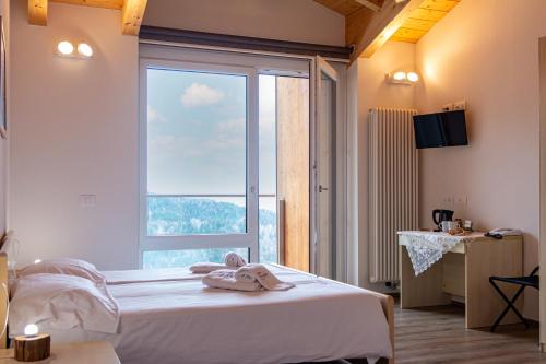 a bedroom with a bed and a large window at Albergo Croce d'Aune in Pedavena