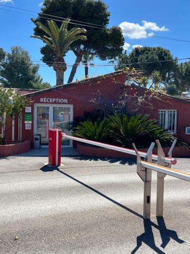 um banco em frente a um edifício vermelho em Mobil home Petit Paradis, 6 personnes, Bord de mer, Camping Del Mar Village em Argelès-sur-Mer