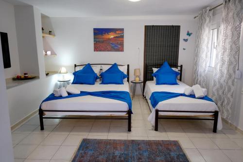 2 Betten in einem Zimmer mit blauen Kissen in der Unterkunft CHEZ KYRIAKI in Kavala
