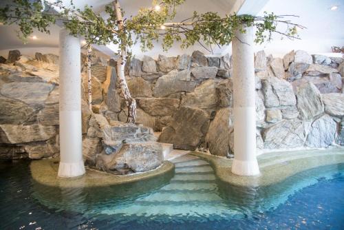 a pool in a resort with a rock wall at Alpenhotel Weitlanbrunn in Sillian
