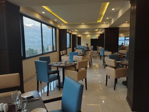 a dining room with tables and chairs and windows at Avari Xpress Gilgit in Gilgit