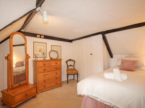 a bedroom with a bed and a dresser and a mirror at Vine Cottage in Studland
