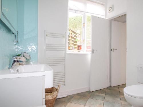 uma casa de banho branca com um lavatório e um WC em Vine Cottage em Studland