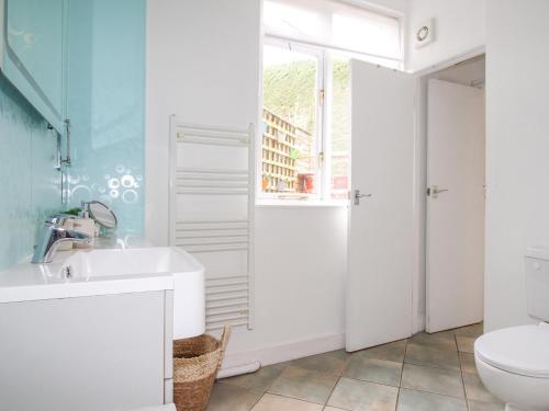 a white bathroom with a sink and a toilet at Vine Cottage in Studland