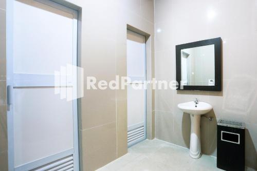 y baño con ducha, lavabo y espejo. en Edotel Syariah Nilam Sari Mitra RedDoorz, en Pekanbaru