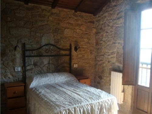 - une chambre avec un lit dans un mur en pierre dans l'établissement House 2 Bedrooms 3474, à Muxía