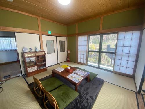 um quarto com uma mesa, um sofá e janelas em Nikko PRIVATE INN WA NODOKA em Nikko