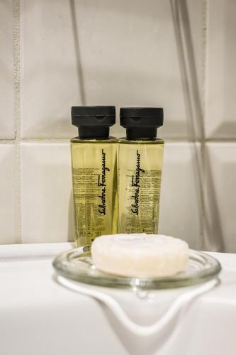 two bottles of liquids sitting on a glass plate at Foresteria Villa Puccini Casa per Ferie-Holiday Home in Torre del Lago Puccini