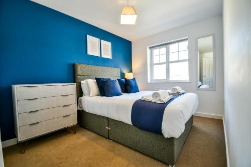 um quarto com uma cama grande e paredes azuis em Einstein House Horizon Stays em Stockton-on-Tees