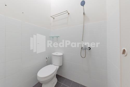 a white bathroom with a toilet and a shower at 158 Guest House Syariah RedPartner in Bandung