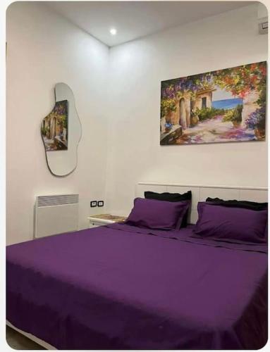 Sidi Daoud的住宿－Appartement Cosy aux Jardins de Carthage，一间卧室配有一张紫色床,墙上挂有绘画作品