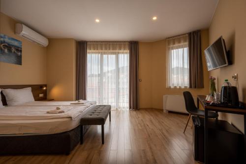 a hotel room with a bed and a large window at Family Hotel Konstantinovi in Kyustendil