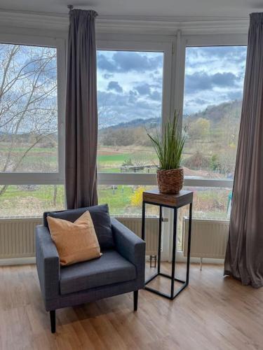 a blue chair sitting in front of a large window at Modernes Apartment mit Balkon, Parkplatz und Smart Tv bis zu 10 Personen in Weinstadt