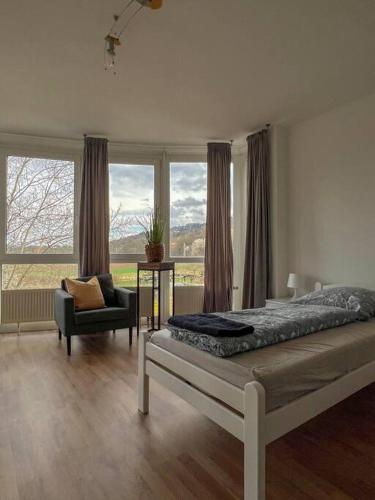 a bedroom with a bed and a chair and windows at Modernes Apartment mit Balkon, Parkplatz und Smart Tv bis zu 10 Personen in Weinstadt