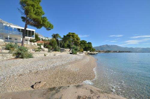 a beach with a house and the water at LaidBack Apartments in Orebić