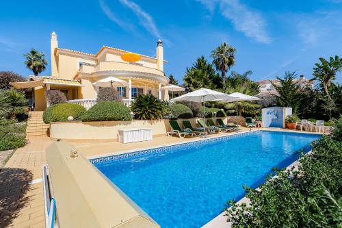 a villa with a swimming pool in front of a house at Casa Mandalin in Carvoeiro