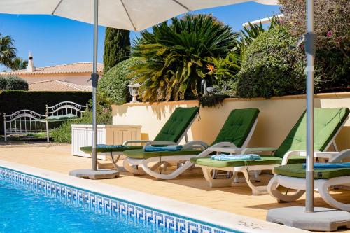 a pool with lounge chairs and an umbrella and a swimming pool at Casa Mandalin in Carvoeiro