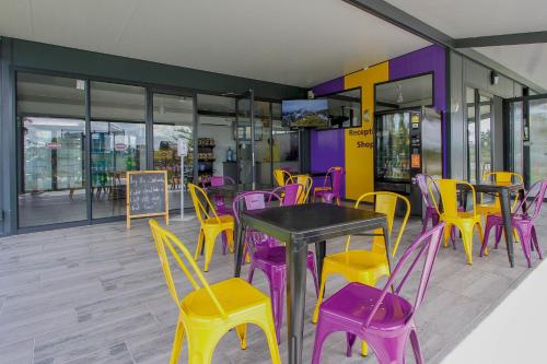 un restaurant avec des tables et des chaises pourpres et jaunes dans l'établissement SleepOver Orpen Gate, à Acornhoek