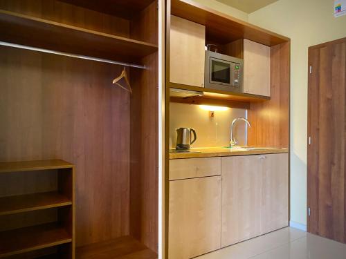 a small kitchen with wooden cabinets and a microwave at Holiday Resort Tatry in Veľká Lomnica