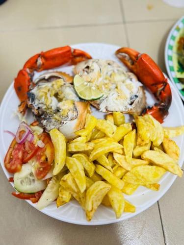 a plate of food with lobster and chips on a table at Lui Ushongo Beach House in Pangani