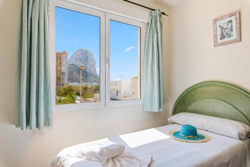 ein Schlafzimmer mit einem Bett mit einem Hut und einem Fenster in der Unterkunft Apartamento Arenal 6 - PlusHolidays in Calpe