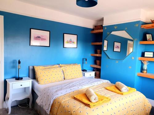 1 dormitorio con paredes azules y 1 cama con almohadas amarillas en The Bee House Brighton. A holiday home by the sea., en Brighton & Hove