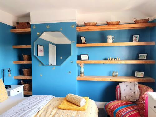 1 dormitorio con paredes azules y estanterías de madera en The Bee House Brighton. A holiday home by the sea., en Brighton & Hove