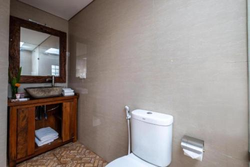 a bathroom with a toilet and a sink and a mirror at D'jineng Rice Terrace Canggu in Canggu