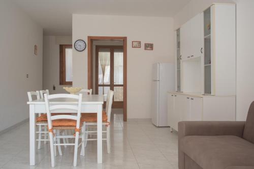 una cucina e una sala da pranzo con tavolo e sedie bianchi di Residence Via Milano a Marina di Mancaversa