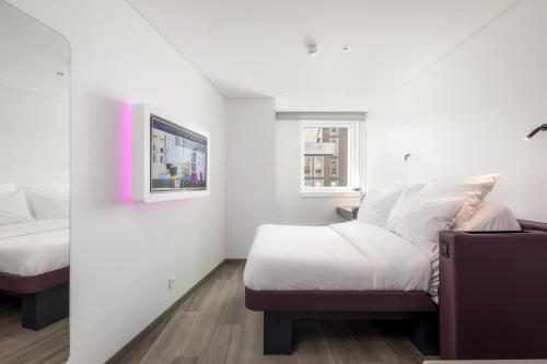 a bedroom with a bed and a tv on a wall at YOTEL Porto in Porto