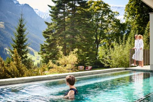 阿德爾博登的住宿－Bellevue Parkhotel & Spa - Relais & Châteaux，妇女在度假村的游泳池游泳