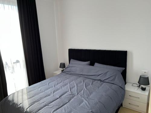 a bedroom with a large bed with a black headboard at Sunlit Coast Apartment Durrës in Durrës