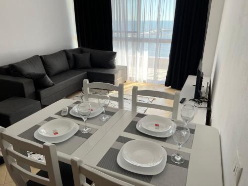 una mesa de comedor con platos y copas de vino. en Sunlit Coast Apartment Durrës en Durrës