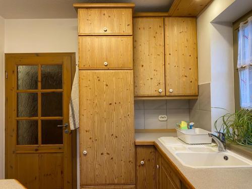 uma cozinha com armários de madeira e um lavatório em Ferienhaus Brühler em Maierhof