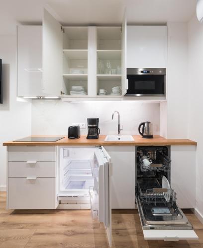 a kitchen with white cabinets and an open dishwasher at Szikla apartmanok Visegrád in Visegrád