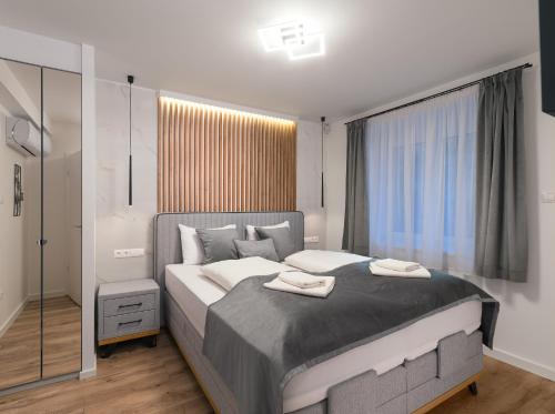 a bedroom with a large bed with two towels on it at Szikla apartmanok Visegrád in Visegrád