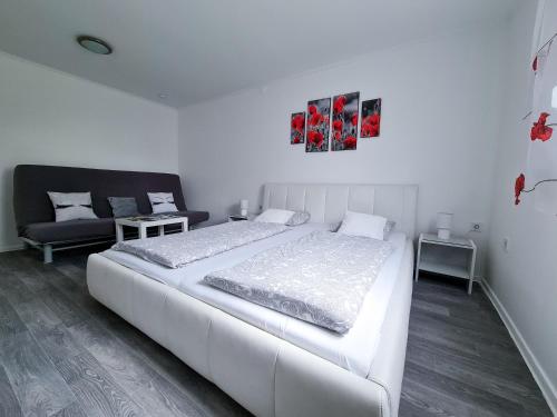 a white bedroom with a large bed and a couch at Tündérlak Nyaraló Békésszentandrás in Békésszentandrás