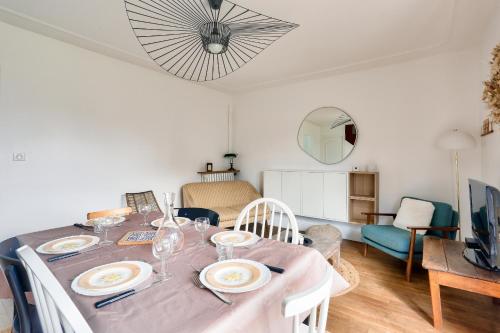 une salle à manger avec une table avec des assiettes et des verres à vin dans l'établissement 1km plage du Prieuré- Dinard- Maison pour 6, à Dinard